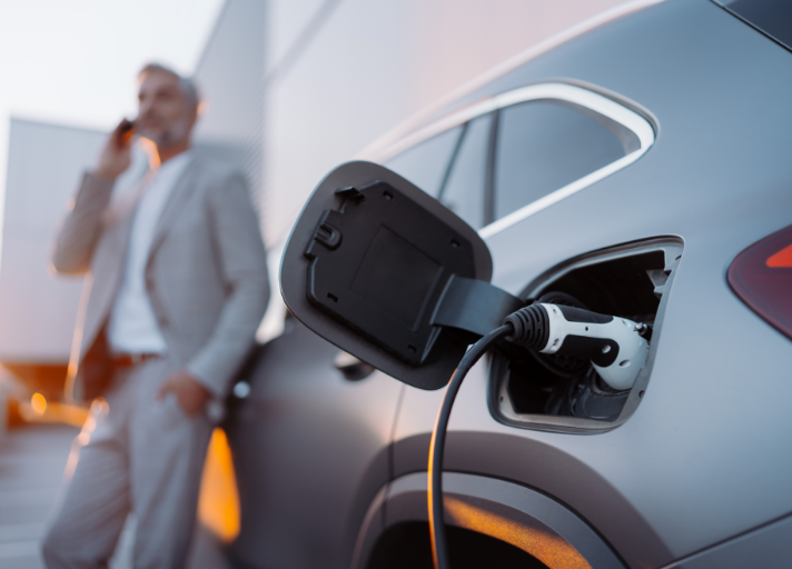 businessman-phoneing-while-charging-car-at-electri-2022-12-22-13-39-45-utc